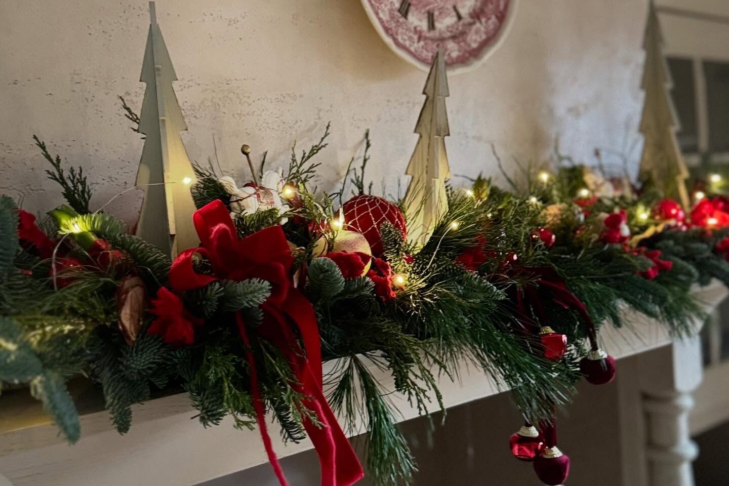 Świąteczna girlanda z gałązek iglastych, czerwonych kokard i światełek