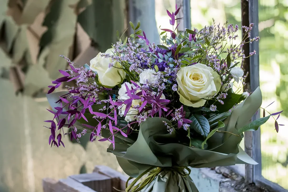 Kompozycja z białych róż i fioletowych dodatków w naturalnym świetle